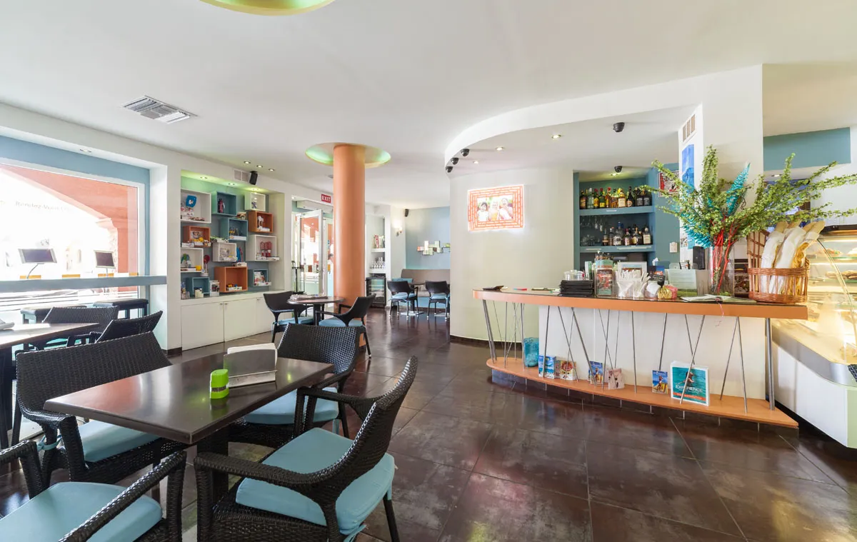 Bright interior of Rendez-Vous Lounge with aqua seating and pastry counter
